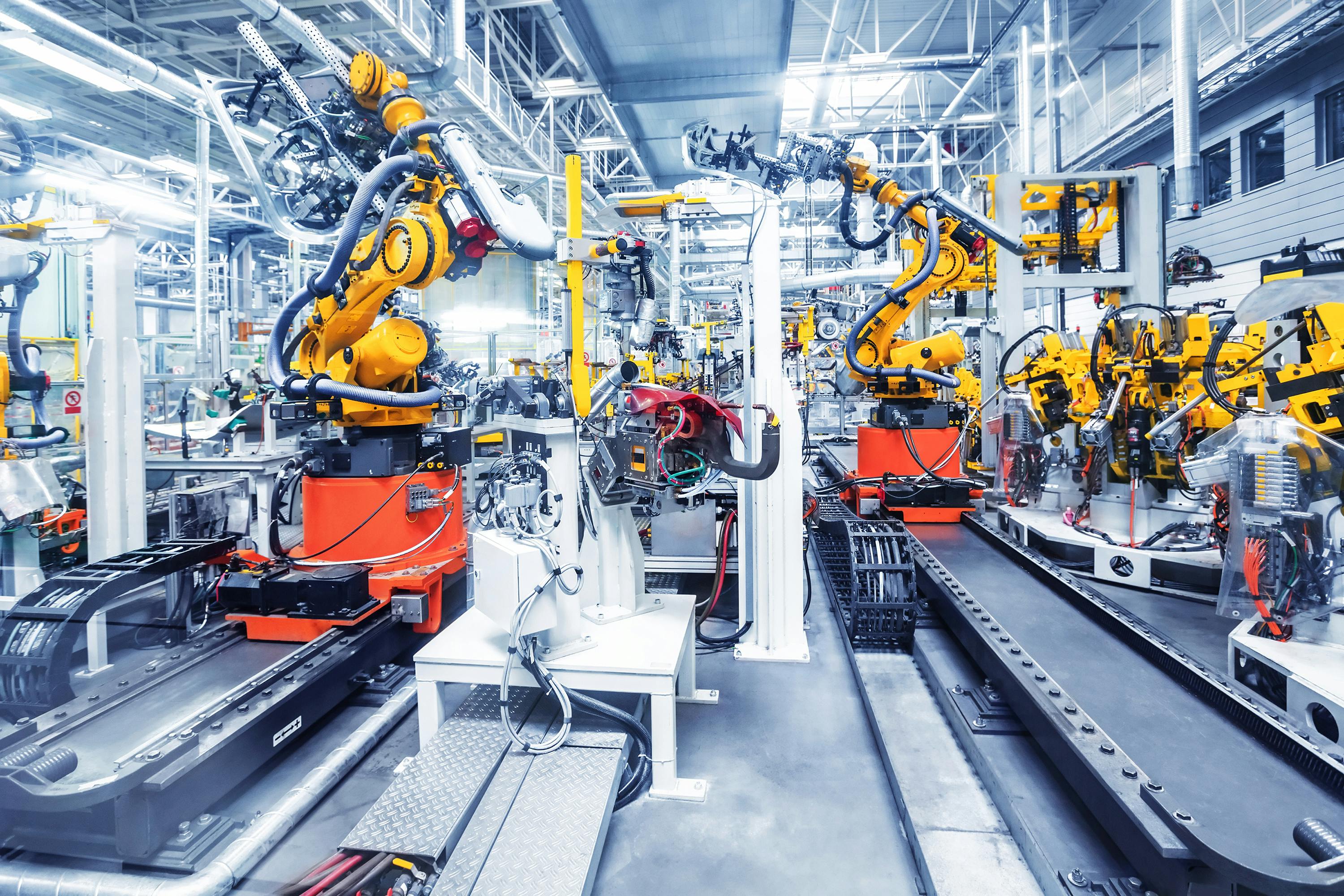 Inside of a factory with robotic arms assembling large machinery